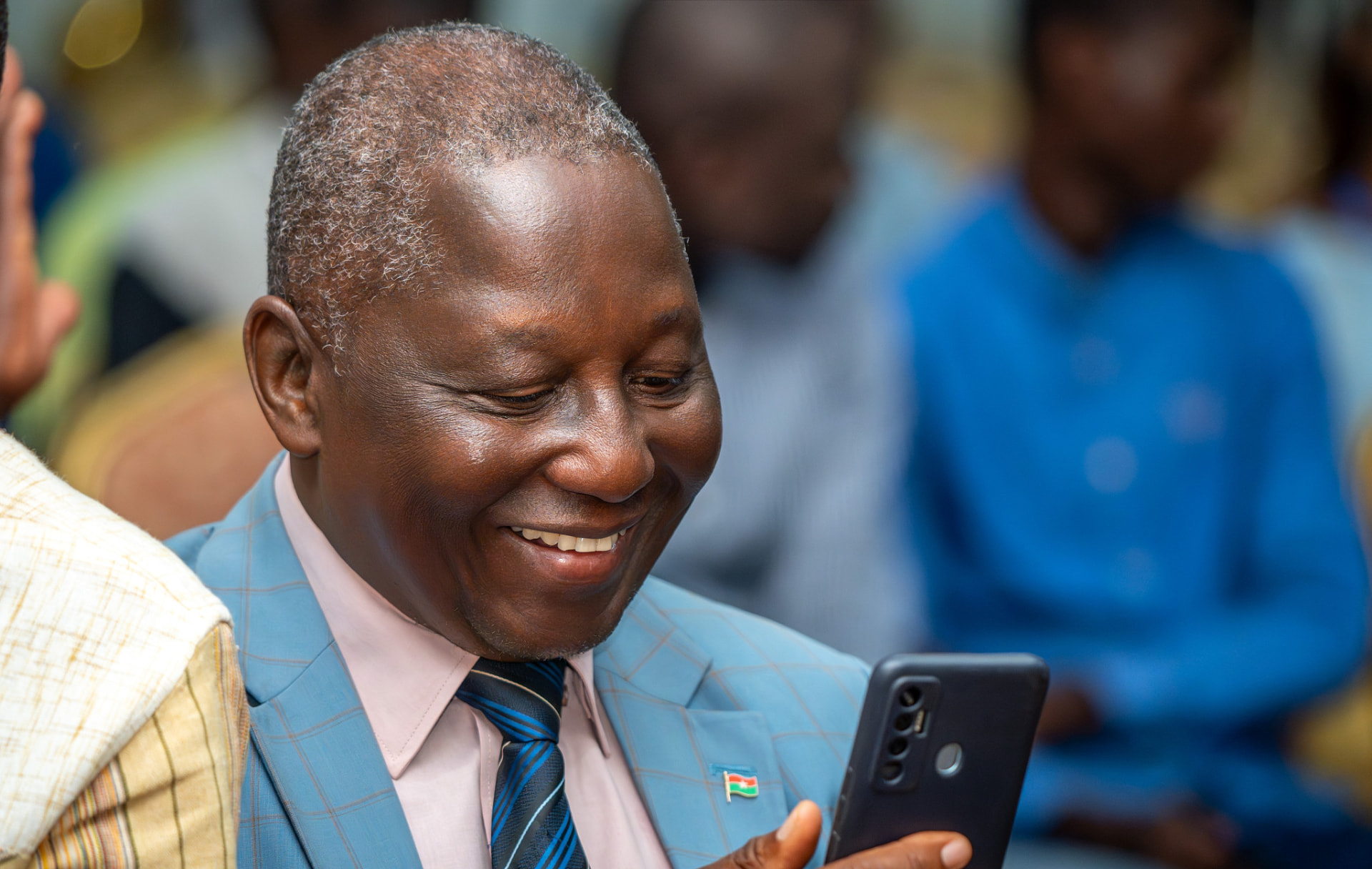 Invité en costume bleu souriant devant son téléphone