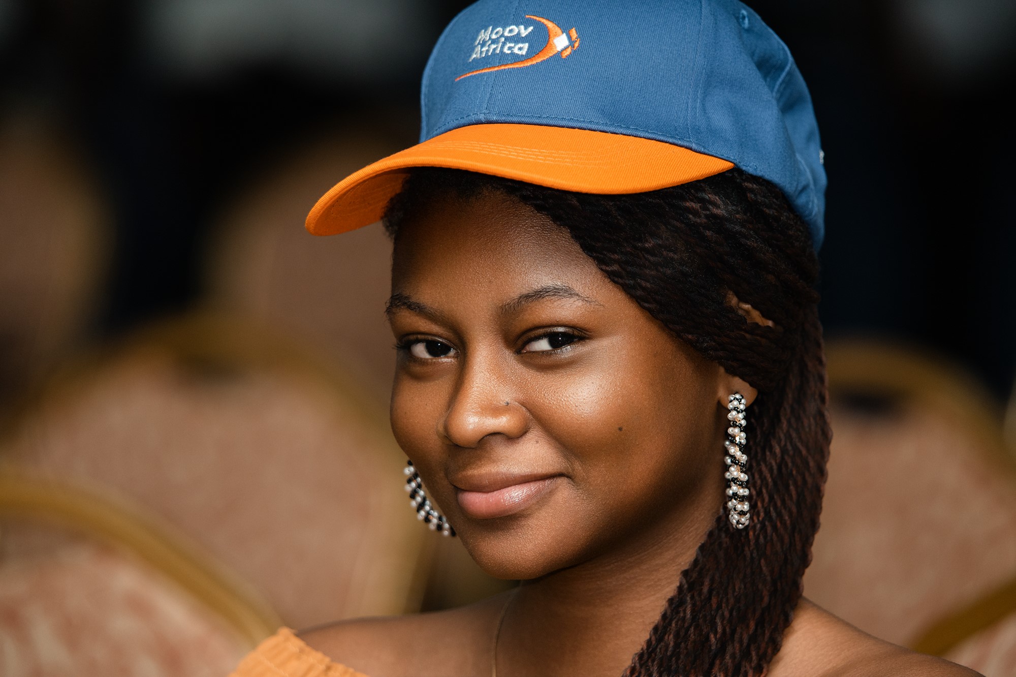 Jeune femme à la casquette bleue et orange, sourire discret